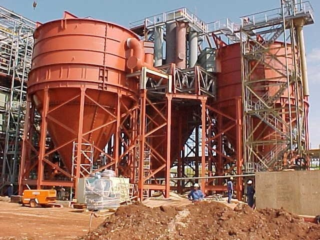 Large red thickener tanks and steelwork under construction at a mine site
