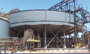 Large thickener tank under construction with steelwork and scaffolding at a mine site